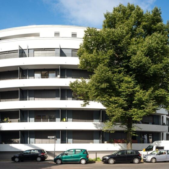 Moderne Wohnanlage mit runder Architektur und grünen Bäumen in der Umgebung.