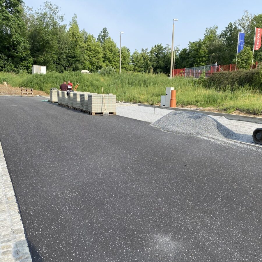Bauarbeiten an einer neuen Straße mit Pflastersteinen und Maschinen im Hintergrund.