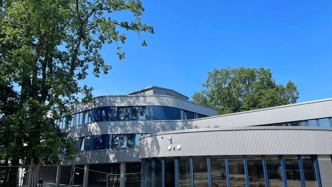 Johannes-Kepler-Gymnasium mit großen Fenstern und grünem Umfeld unter blauem Himmel.