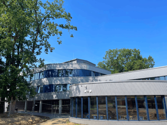 Johannes-Kepler-Gymnasium mit großen Fenstern und grünem Umfeld unter blauem Himmel.