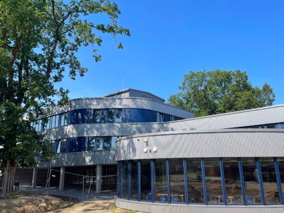 Johannes-Kepler-Gymnasium mit großen Fenstern und grünem Umfeld unter blauem Himmel.