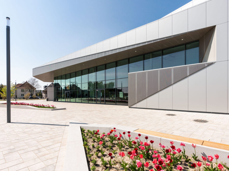 Stadthalle Rheda-Wiedenbrück mit großen Fenstern und bunten Tulpen im Vordergrund.