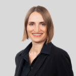 Professionelles Porträt einer Frau mit blonden, schulterlangen Haaren in schwarzer Kleidung.