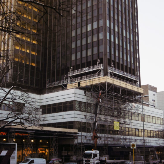 Bauarbeiten an einem Hochhaus 8Steglitzer Kreisel) mit Gerüst und Stadtansicht im Hintergrund.