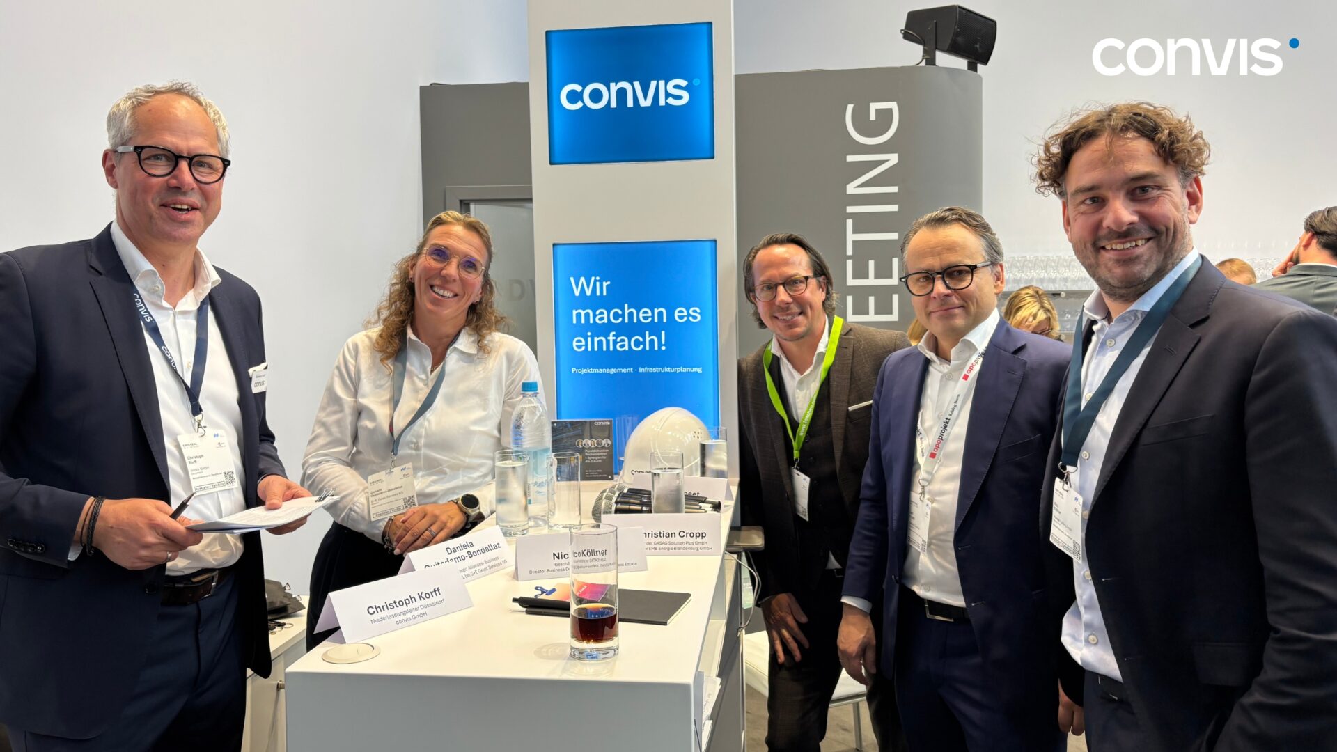 Fünf Personen am Convis-Stand bei einer Messe, freundliche Gespräche und Networking.