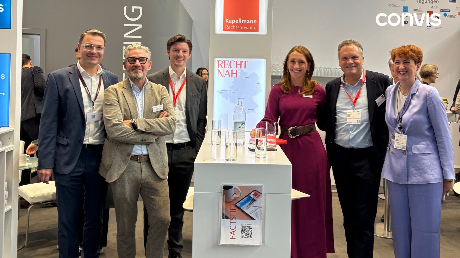 Networking-Event mit Fachleuten in Anwaltskanzlei-Kleidung am Stand von Convis.