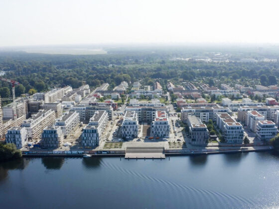 Moderne Wohnsiedlung am Wasser mit Neubauten und grüner Umgebung.