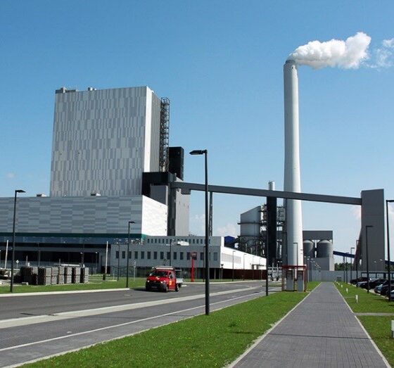 Moderne Industrieanlage mit Schornstein und Fahrzeugen auf dem Parkplatz.