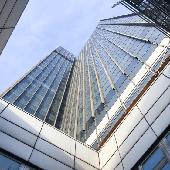 Blick nach oben auf moderne Wolkenkratzer mit Glasfassade und klar blauem Himmel.