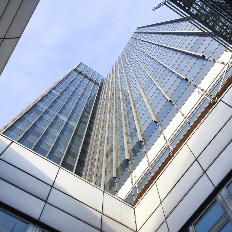 Blick nach oben auf moderne Wolkenkratzer mit Glasfassade und klar blauem Himmel.