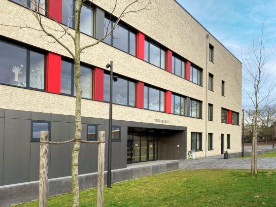 Oberschule Billerbeck mit rotem Akzent und großzügiger Eingangsgestaltung in urbaner Umgebung.