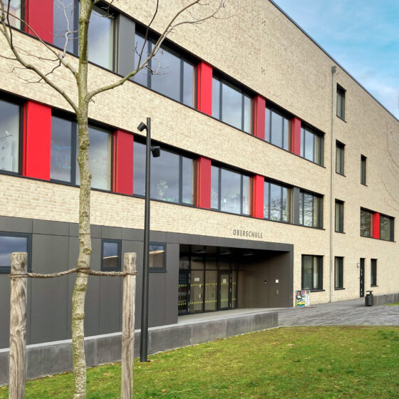 Oberschule Billerbeck mit rotem Akzent und großzügiger Eingangsgestaltung in urbaner Umgebung.