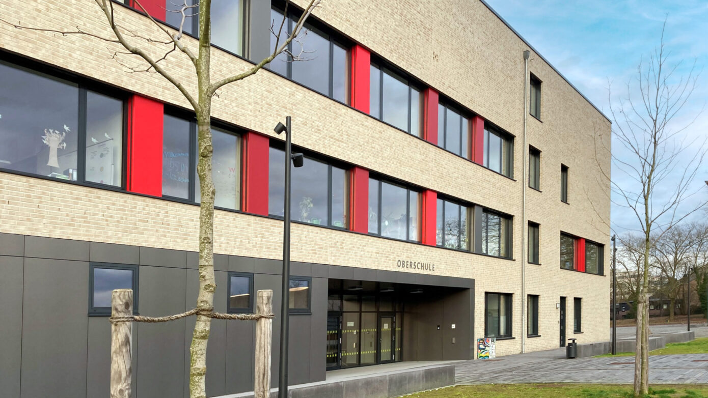 Oberschule Billerbeck mit rotem Akzent und großzügiger Eingangsgestaltung in urbaner Umgebung.