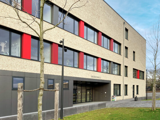 Oberschule Billerbeck mit rotem Akzent und großzügiger Eingangsgestaltung in urbaner Umgebung.