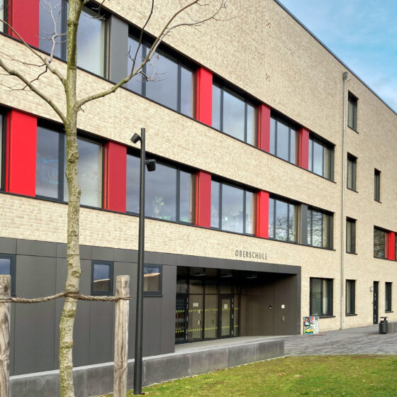 Oberschule Billerbeck mit rotem Akzent und großzügiger Eingangsgestaltung in urbaner Umgebung.