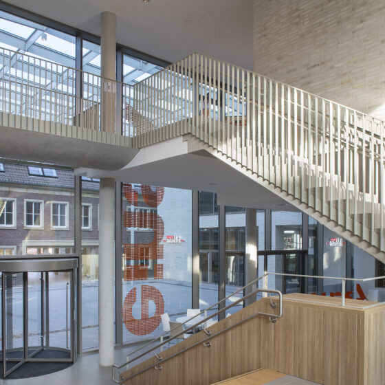 Moderne Treppe im hellen Foyer mit großen Fenstern und Empfangstresen.