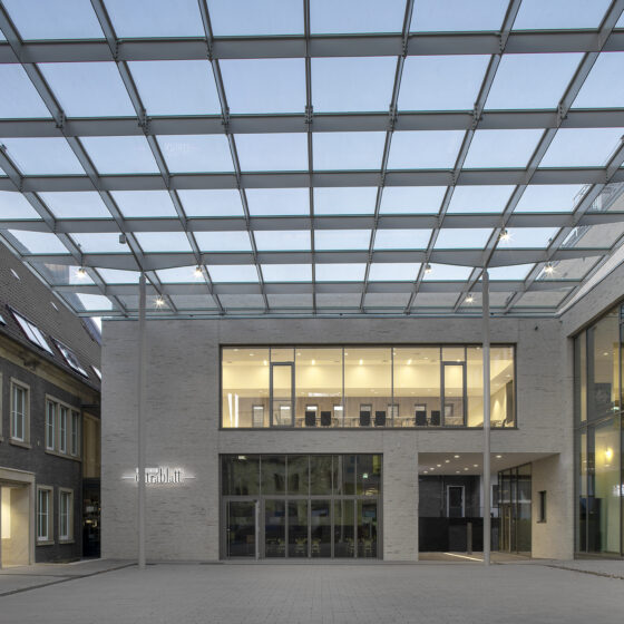 Moderne Architektur mit Glasdach und zeitgenössischem Design in urbaner Umgebung.