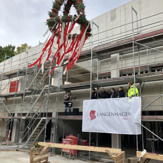 Richtfest der IGS Langenhagen SÜD. Die feierliche Richtkrone wird bei Bauarbeiten in Langenhagen gehisst. Bauleiter und Team beobachten.
