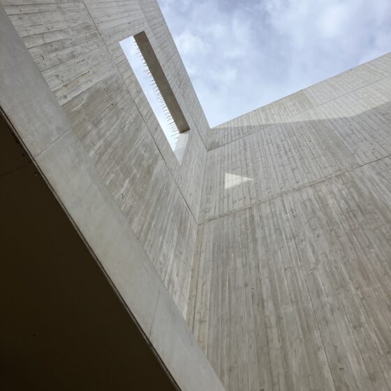 Architektonisches Detail eines Betongebäudes mit geöffnetem Himmel und strukturierten Wänden.