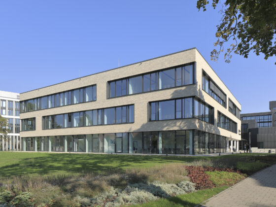 IHK-Nord Westphalen Münster mit großen Fenstern und grüner Umgebung unter blauem Himmel.