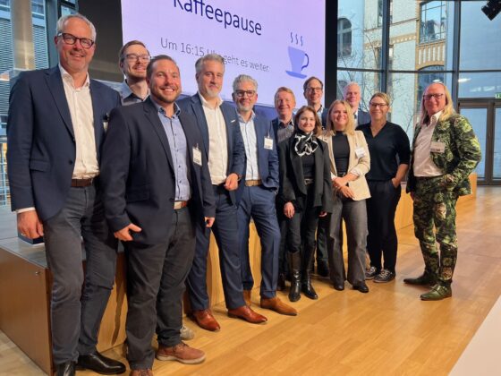 Gruppenfoto von Konferenzteilnehmern während einer Kaffeepause, lächelnd und entspannt.