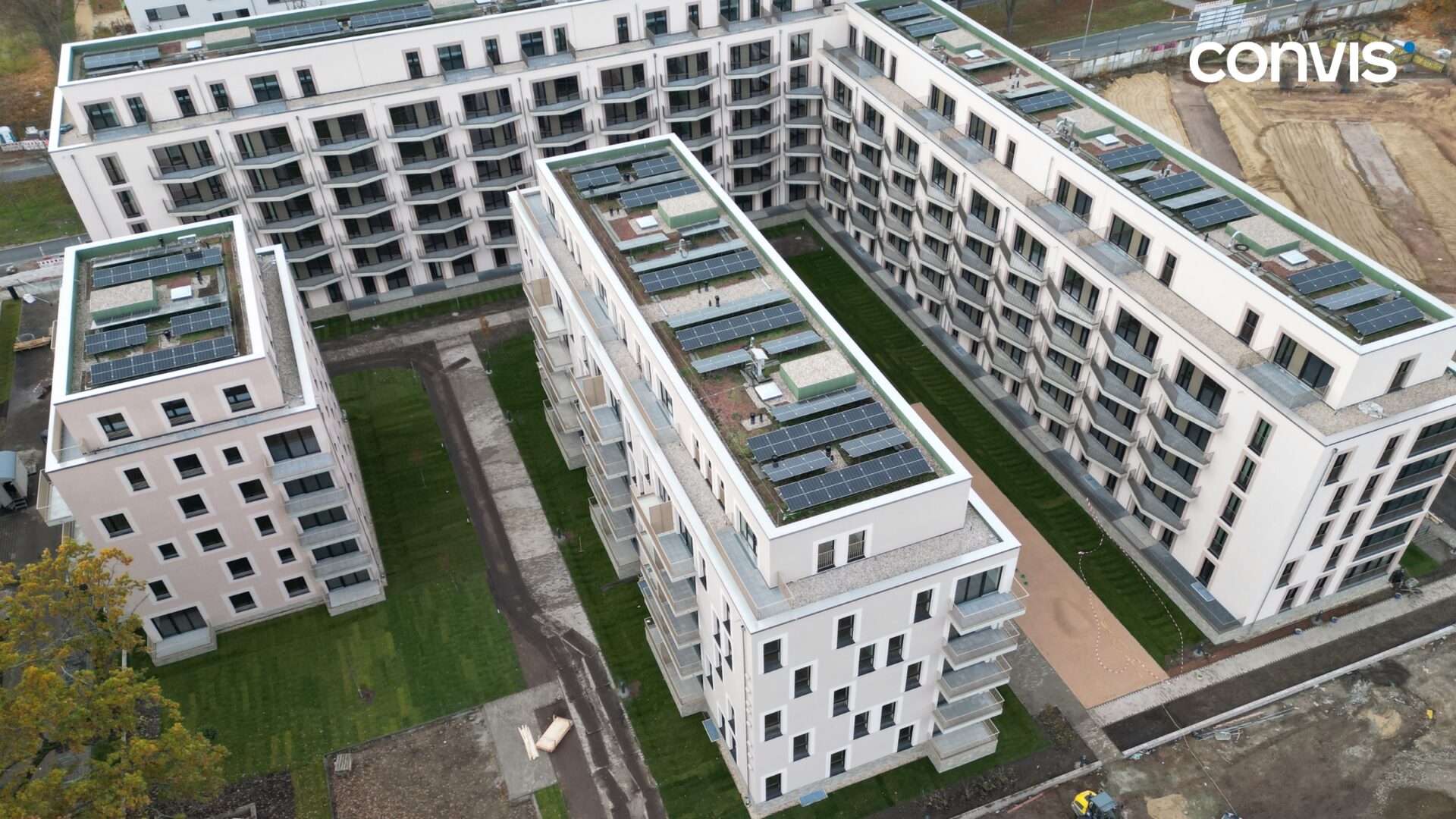 Moderne Wohnanlage mit begrünten Dächern und Solarpanels in städtischer Umgebung.