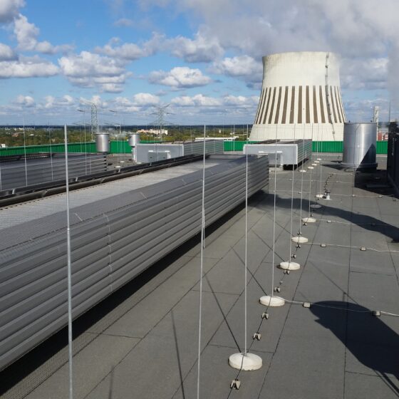 Dachansicht mit Kühlturm und Rohren, unter blauem Himmel mit Wolken.