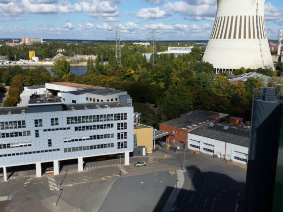 Ansicht von oben des Müllheizkraftwerks Ruhleben mit modernen Gebäuden und Kühlturm vor bewölktem Himmel.