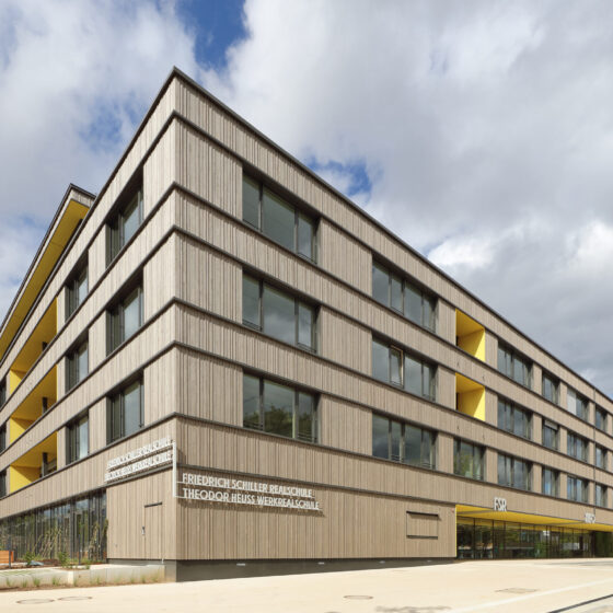Ansicht des Eingangsbereichs der Friedrich-Schiller-Realschule und Theodor-Heuss-Werkrealschule in Stockbrünnle, Böblingen, mit großen Fenstern und Holzfassade.