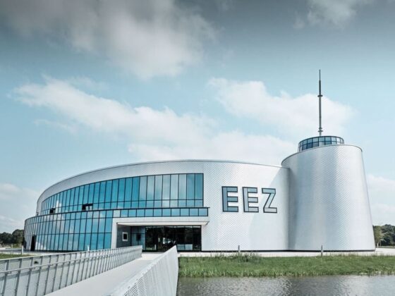 Modernes Gebäude des EEZ mit Glasfassade und umliegendem Wasser, ideal für Besucher.