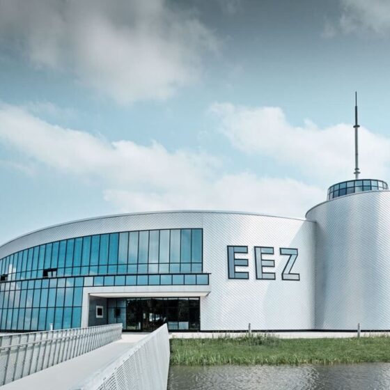 Modernes Gebäude des EEZ mit Glasfassade und umliegendem Wasser, ideal für Besucher.