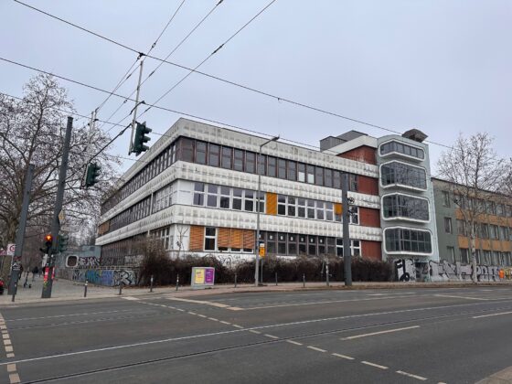 Verlassenes Gebäude mit Graffiti und Straßenverkehr in städtischer Umgebung.