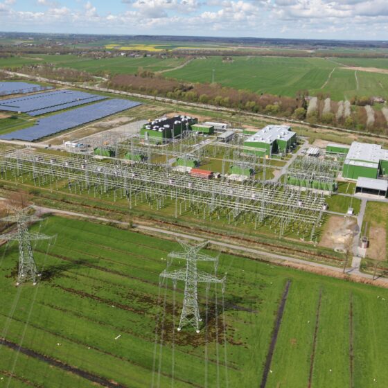 Ansicht BorWin6 mit Windkraft, Solarpanelen und Hochspannungsleitungen in ländlicher Umgebung.