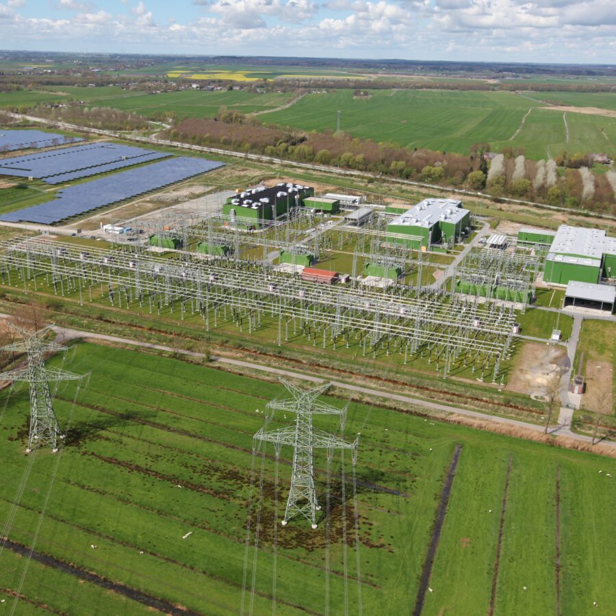Ansicht BorWin6 mit Windkraft, Solarpanelen und Hochspannungsleitungen in ländlicher Umgebung.
