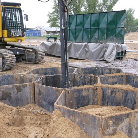 Bauplatz mit Bagger und ausgehobenen Gruben für Fundamentarbeiten.