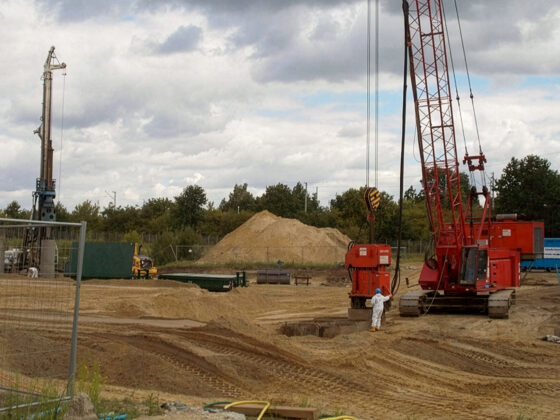 Baustelle auf den GESA-Gelände mit Kränen, Baggern und Sandhügel unter bewölktem Himmel.
