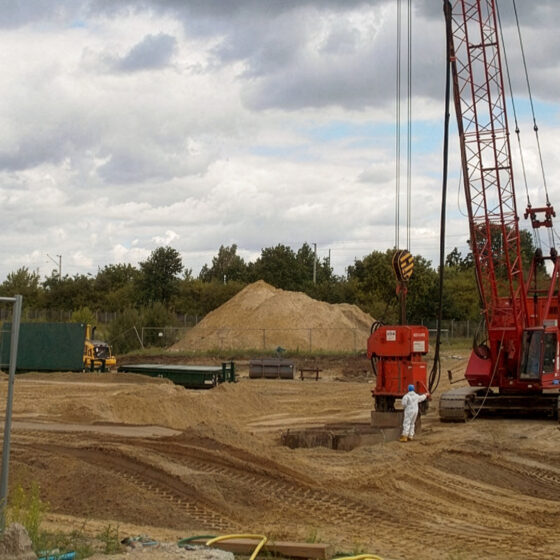 Baustelle auf den GESA-Gelände mit Kränen, Baggern und Sandhügel unter bewölktem Himmel.