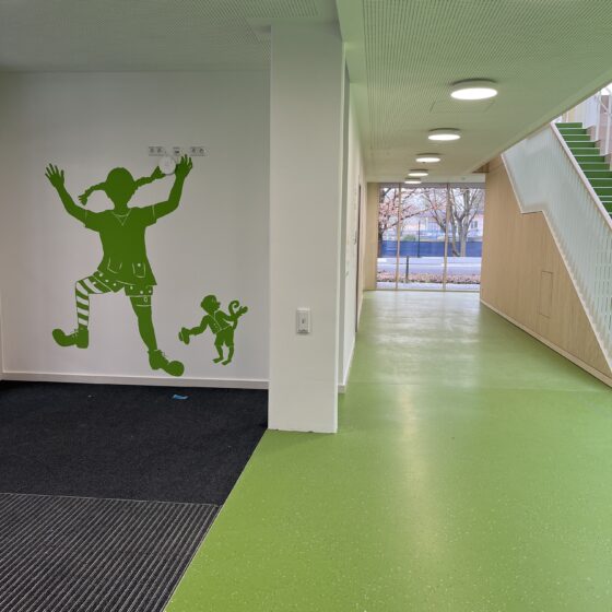 Bunte Wandgestaltung mit Kindern in einem modernen, hellen Flur in der Astrid-Lindgren-Grundschule.