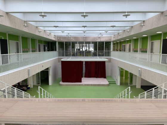 Astrid-Lindgren Schule von innen mit grünen Wänden, Bühne und großzügigem, lichtdurchflutetem Raum.