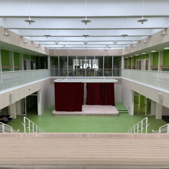 Astrid-Lindgren Schule von innen mit grünen Wänden, Bühne und großzügigem, lichtdurchflutetem Raum.