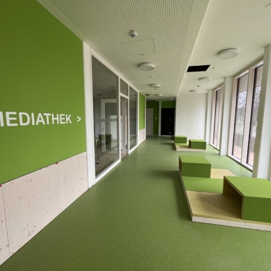 Moderne Mediathek mit grünen Wänden und kreativen Sitzgelegenheiten im Innenbereich.