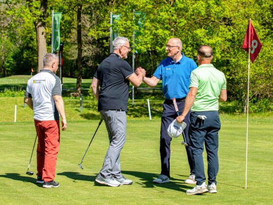 Freundliches Golfspiel: Vier Männer feiern einen gelungenen Schlag auf dem Golfplatz.