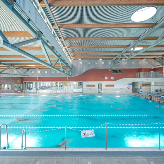 Helles Schwimmbad mit Wasserfläche und modernen architektonischen Elementen.