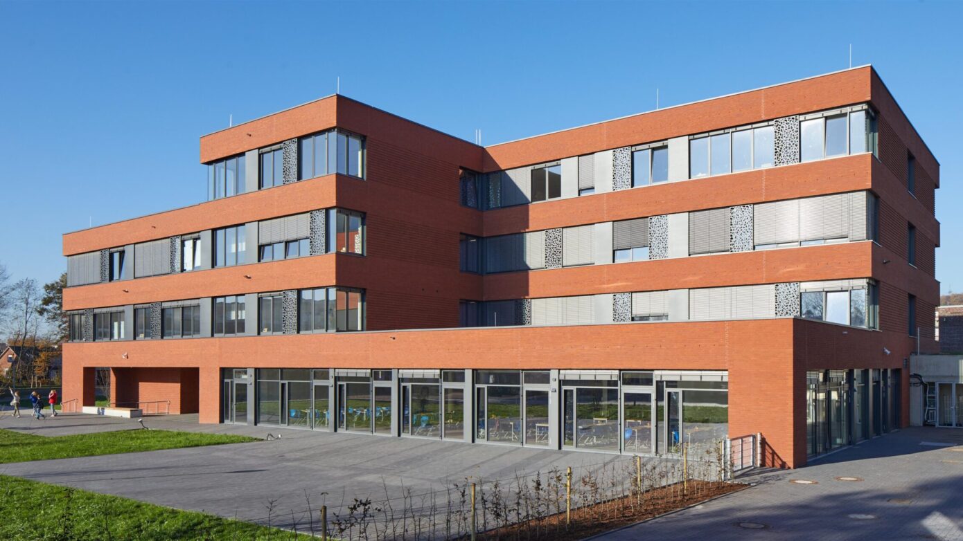Integrierte Gesamtschule Ibbenbüren mit roten Ziegeln und großen Fenstern in sonniger Umgebung.