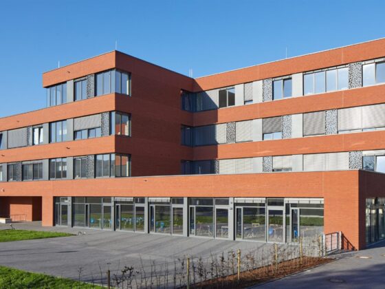 Integrierte Gesamtschule Ibbenbüren mit roten Ziegeln und großen Fenstern in sonniger Umgebung.