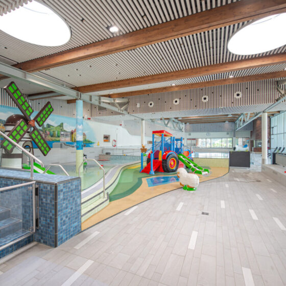 Buntes Hallenbad mit Spielbereich, Wasserrutsche und kinderfreundlichem Design.