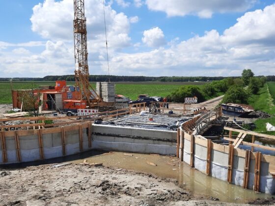 Bauarbeiten an einer Baustelle mit Kran und Fundament in ländlicher Umgebung.