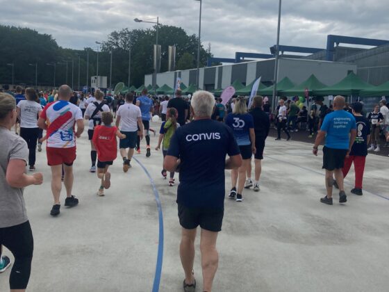 Teilnehmer eines Lauf-Events bewegen sich auf einer Strecke unter bewölktem Himmel.