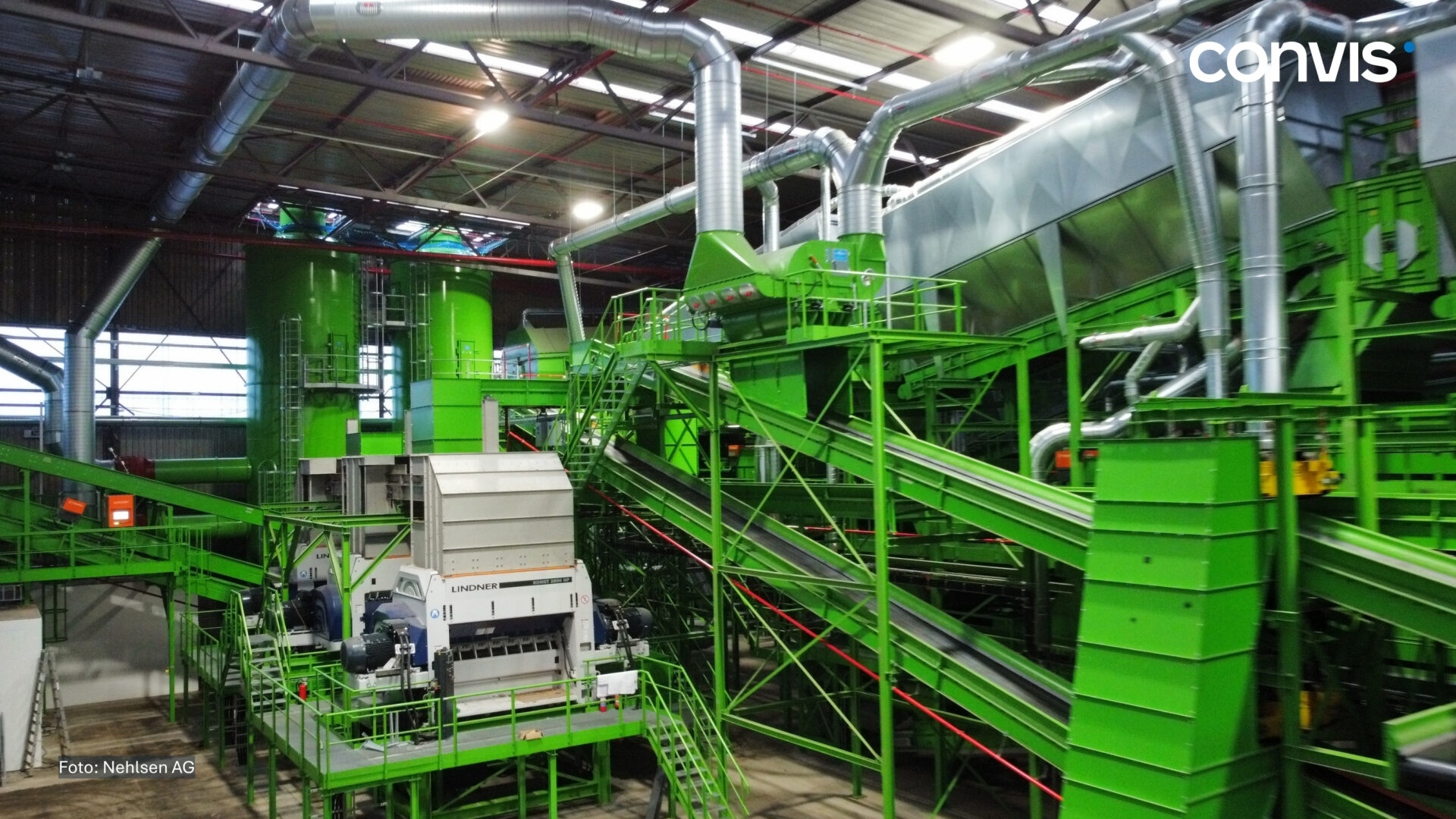 Moderne Recyclinganlage mit grünen Maschinen und Förderbändern in einer Industriehalle.
