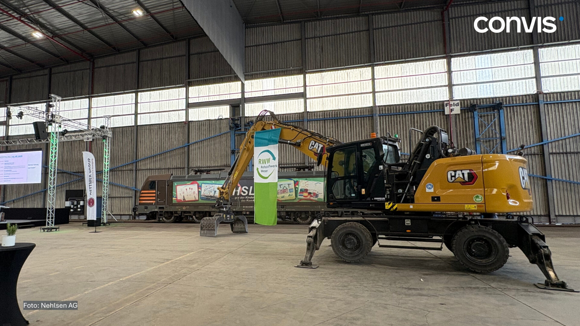 Bagger von CAT in einer großen Lagerhalle während einer Veranstaltung mit Bannern.